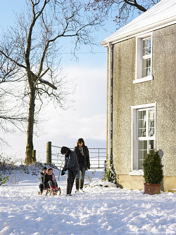 Nicola Nemec with her children playing in the snow outside their farmhouse near Armoy in County Antrim.