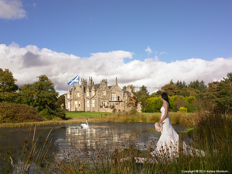 Bride standing by the lake at the Trump International Golf Hotel near Aberdeen in Scotland.